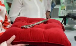 Na zdjęciu czerwona poduszka, na niej nożyce do przecięcia wstęgi
