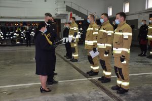 Pierwszy planie w rzędzie trzech strażaków w mundurach bojowych