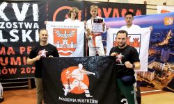 zawodnicy na podium trzymający flagę powiatu