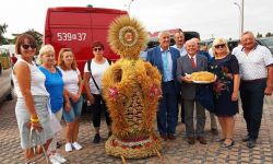 wieniec dożynkowy, wokół ustawiona delegacja dożynkowa z chlebem