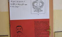 biało czerwony plakat, czarne kontury godła Polski i Piłsudskiego