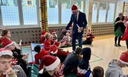 Wicestarosta rozdaje siedzącym dzieciom cukierki