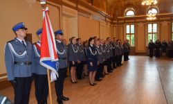 Policjanci trzymający sztandar uformowani w szeregu