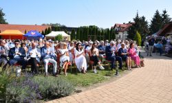 zaproszeni goście siedzący na krzesełkach na terenie pikniku