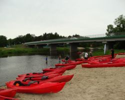 kajaki na plaży, w oddali uczestnicy spływu