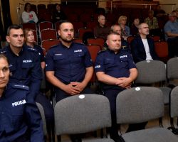 funkcjonariusze policji i mieszkańcy siedzą i słuchają prezentacji