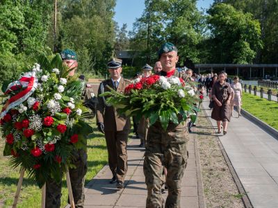 dwaj żołnierze niosą wiązanki w barwach biało-czerwonych