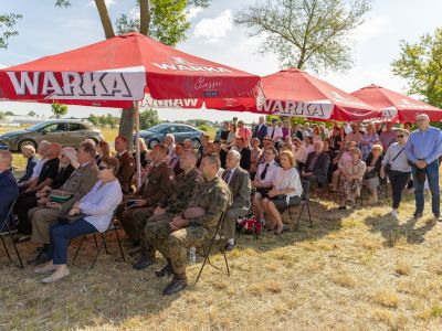 zgromadzeni goście siedzą pod parasolami