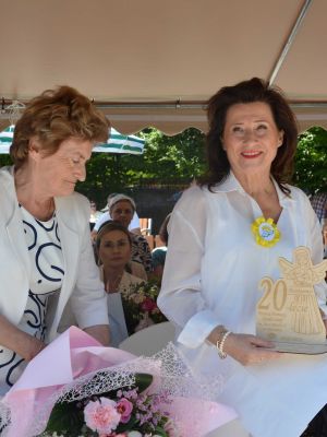 Starosta Nowodworski Magdalena Biernacka na tle pozostałych gości, trzyma w ręku drewnianego aniołka