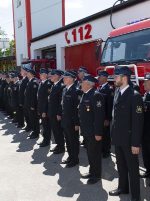 strażacy stoją w szeregu pod budynkiem OSP