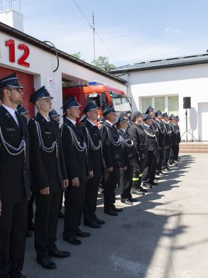 strażacy stoją w szeregu pod budynkiem OSP