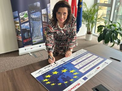Starosta nowodworski Magdalena Biernacka podpisuje tablicę- fundusze europejskie- na budowę ścieżek rowerowych