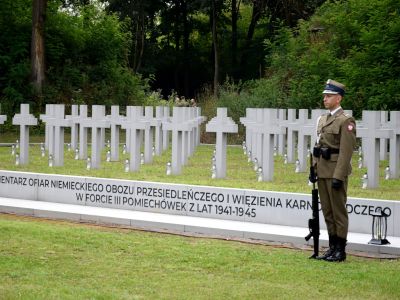 widok na krzyże, cmentarz ofiar niemieckiego obozu na Forcie III, obok stoi wojskowy z bronią