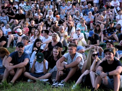 Uczestnicy biorący udział w wydarzeniu siedzą na trawie