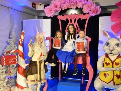 nagrodzeni siedzą na tronie wraz z postacią Alicji