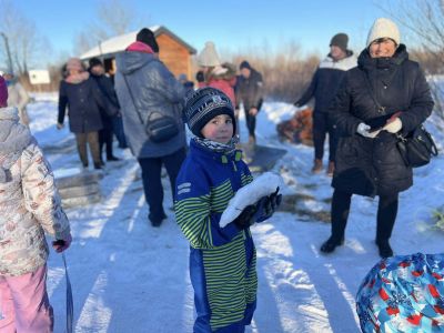 chłopiec trzyma w ręku kawałek śniegu, w tle inni uczestnicy wydarzenia