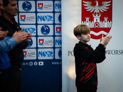 uczestnicy wydarzenia na tle roll-upu powiatu