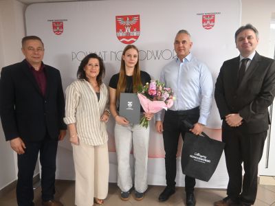 Liwia Kobrzyńska z tatą, Starostą, Wicestarostą i Dyrektorem ZSZ w Nasielsku stoją na tle ścianki powiatu